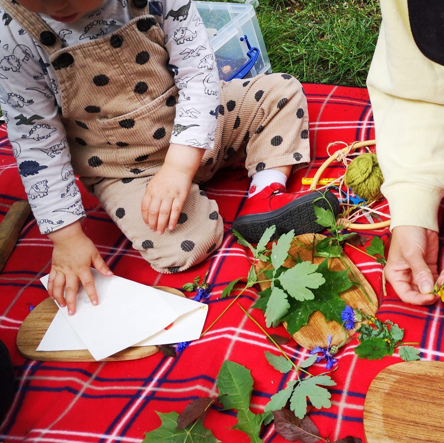 Kleinköper sitzen auf einen Picknick Decke und drücken Blätter im Papier rein.